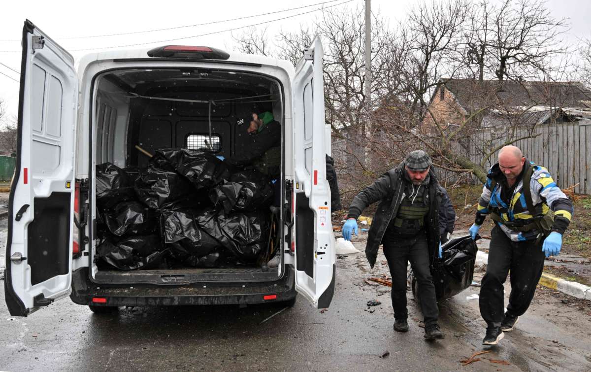 Communal workers carry a body of a civilian man in town of Bucha, not far from the Ukrainian capital of Kyiv on April 3, 2022.