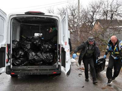 Communal workers carry a body of a civilian man in town of Bucha, not far from the Ukrainian capital of Kyiv on April 3, 2022.