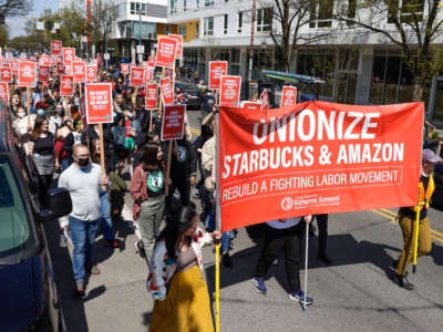 People march in the middle of Broadway during the Fight Starbucks' Union Busting rally and march in Seattle, Washington, on April 23, 2022.