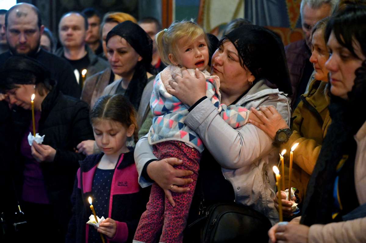 A little girl cries while held by a relative at an outdoor vigil