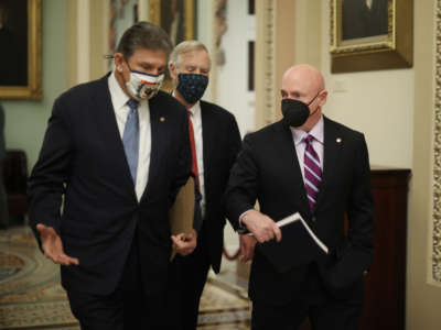 From left, Senators Joe Manchin, Sen. Angus King and Sen. Mark Kelly head to the Senate Chamber at the U.S. Capitol on February 13, 2021, in Washington, D.C.