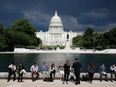 Congressional staffers eat by the reflecting pool during the 36th annual Capitol Hill ice cream party on June 6, 2018, outside the U.S. Capitol in Washington, D.C.