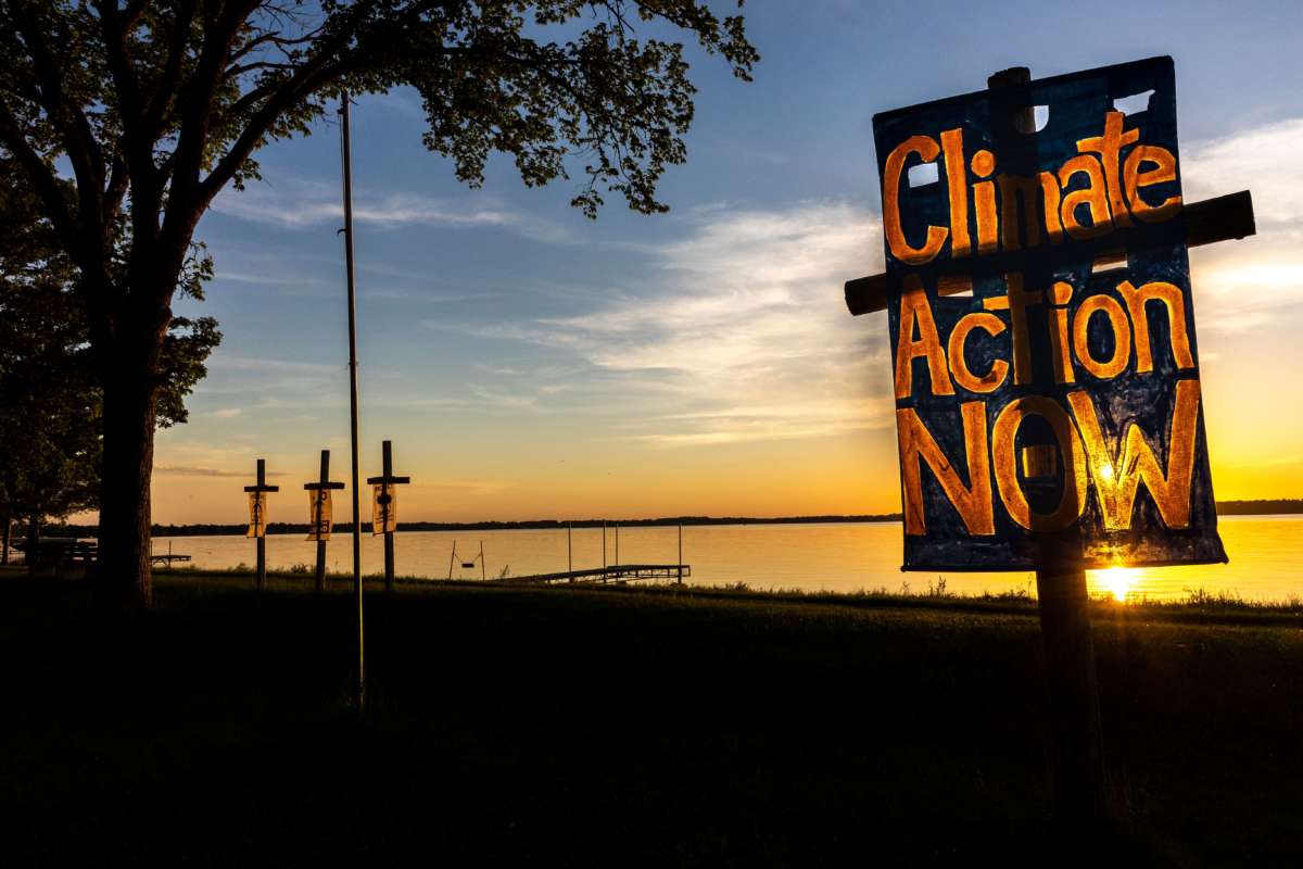 A sign placed near a body of water reads "CLIMATE ACTION NOW"