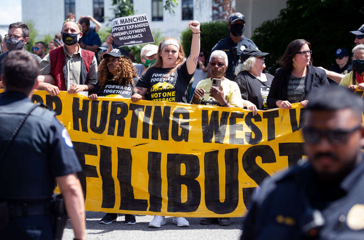 Protesters display a sign calling on Sen. Joe Manchin to abolish the filibuster