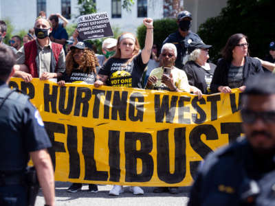 Protesters display a sign calling on Sen. Joe Manchin to abolish the filibuster