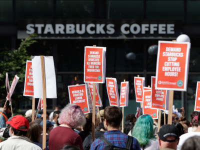 A Starbucks Coffee shop is seen in the background as people gather at Westlake Park during the "Fight Starbucks' Union Busting" rally and march in Seattle, Washington, on April 23, 2022.