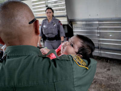 A U.S. Border Patrol agent holds an infant after she and her mother were taken into custody by U.S. Border Patrol agents on July 2, 2019, in McAllen, Texas.