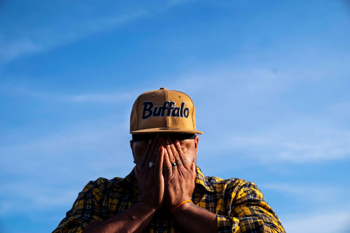 A man wearing a hat that reads "Buffalo" weeps into his hands