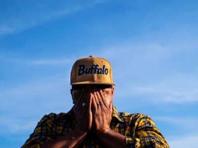 A man wearing a hat that reads "Buffalo" weeps into his hands