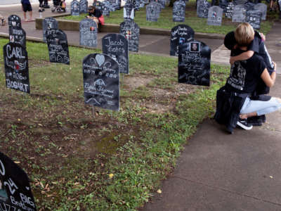 A person embraces a child at a memorial for victims of the opoid crisis