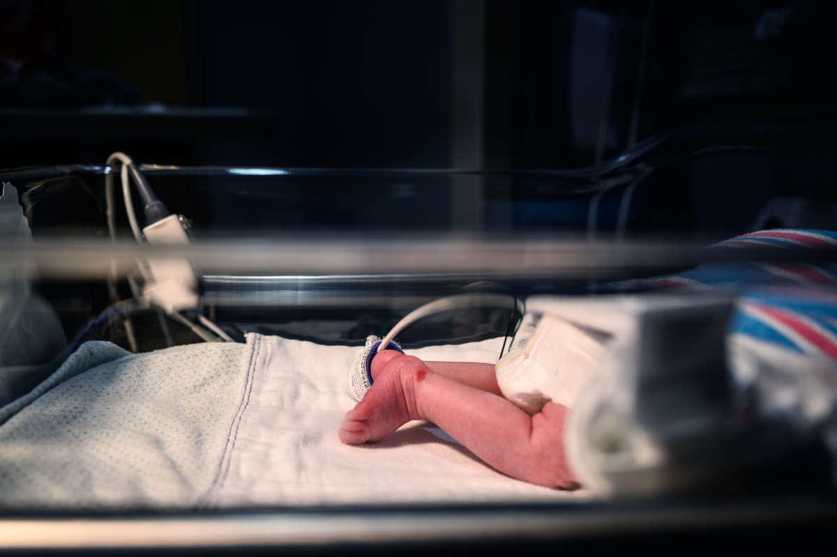 A baby's leg is seen in a neonatal intensive care unit bed