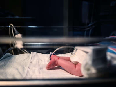 A baby's leg is seen in a neonatal intensive care unit bed