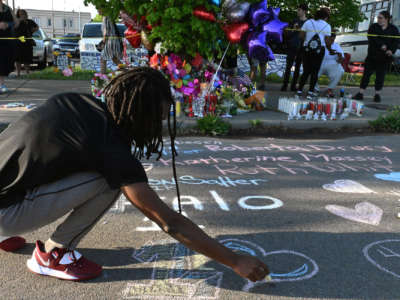 People leave messages at a makeshift memorial near a Tops grocery store in Buffalo, New York, on May 15, 2022, the day after a gunman killed 10 people.