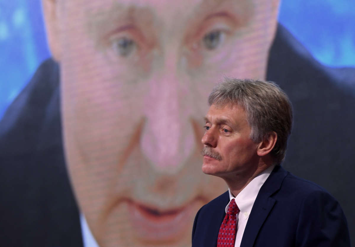 Kremlin spokesman Dmitry Peskov sits in front of a screen displaying Russian President Vladimir Putin addressing his annual press conference via a video link from the Novo-Ogaryovo state residence, at the World Trade Center's congress center in Moscow on December 17, 2020.