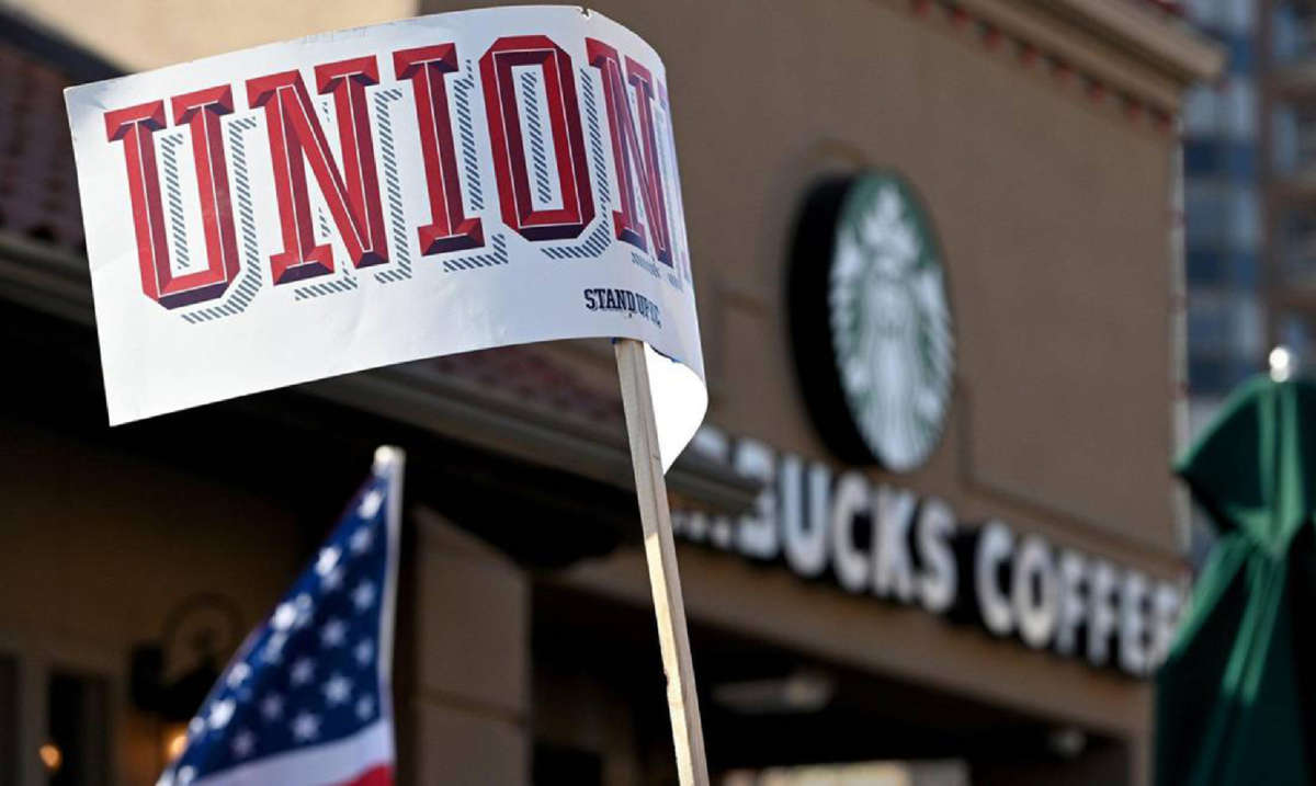 A protester waves a sign that reads 'Union' near the Country Club Plaza Starbucks store where dozens of Starbucks employees and union supporters protested alleged anti-union tactics by the company on March 3, 2022.