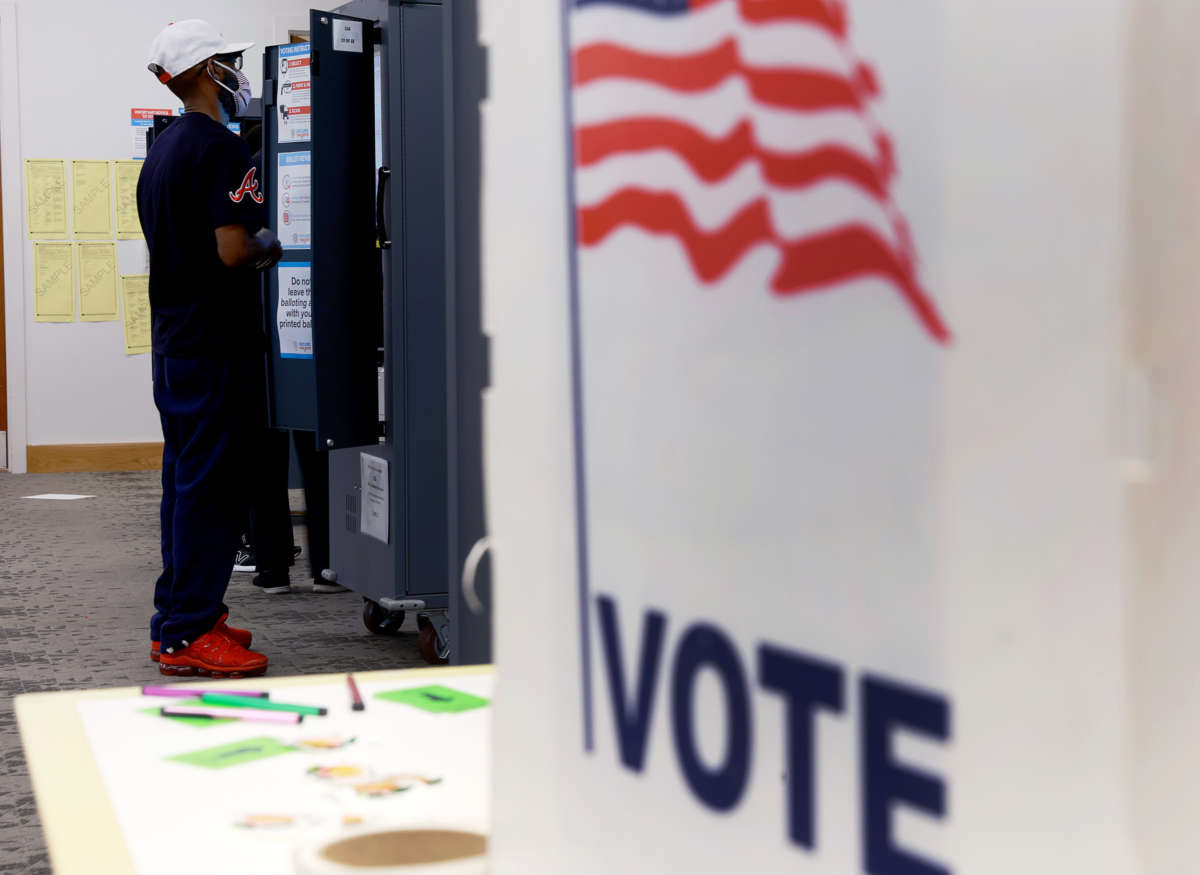 A masked man votes at a booth