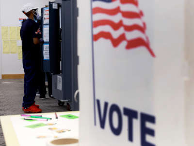 A masked man votes at a booth