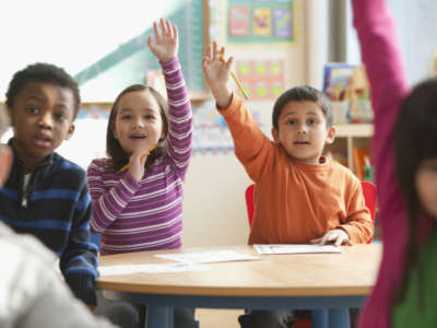 Children in a classroom raising their hands