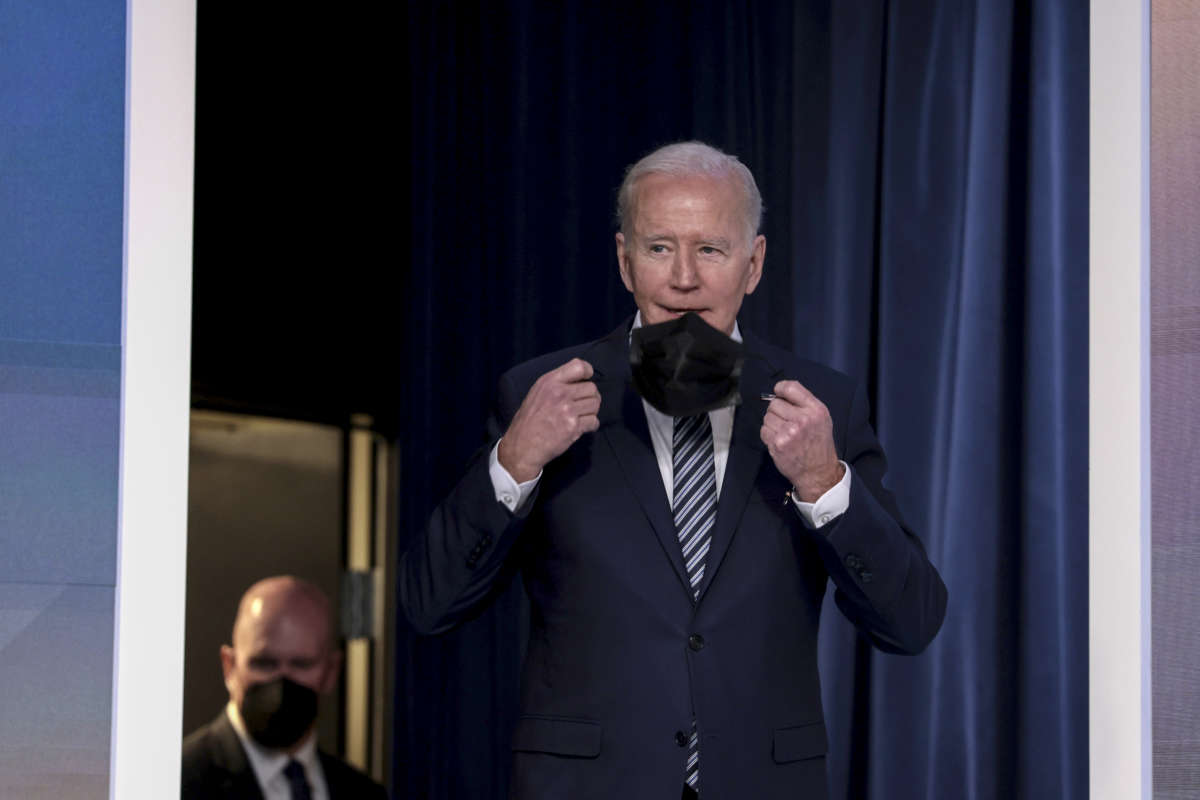 President Joe Biden removes his face mask in the South Court Auditorium of the White House on March 31, 2022, in Washington, D.C.