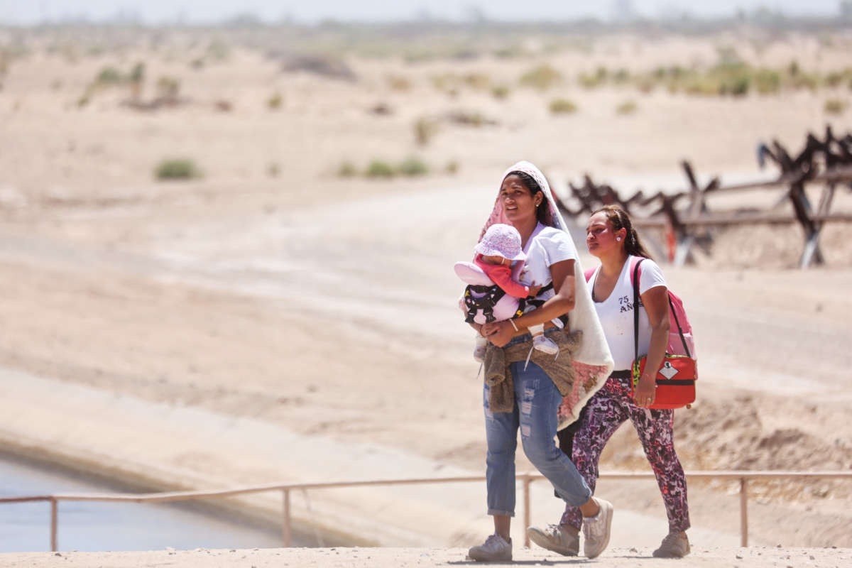An immigrant mother, her infant daughter, and her cousin walk through the desert