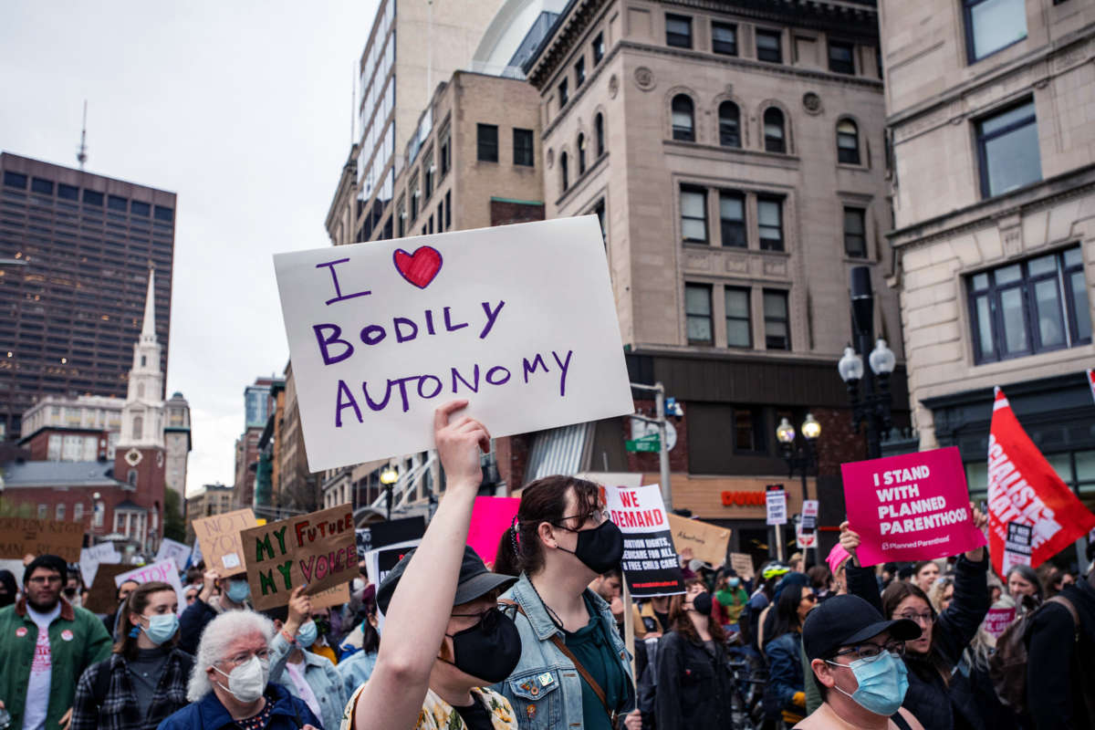 A person marches with a sign reading "I [heart symbol] BODILY AUTONOMY" during an outdoor protest