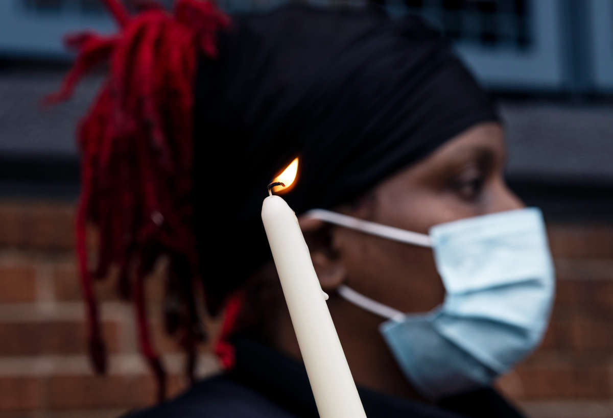 A masked woman holds a candle during an outdoor protest