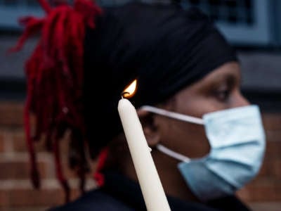 A masked woman holds a candle during an outdoor protest