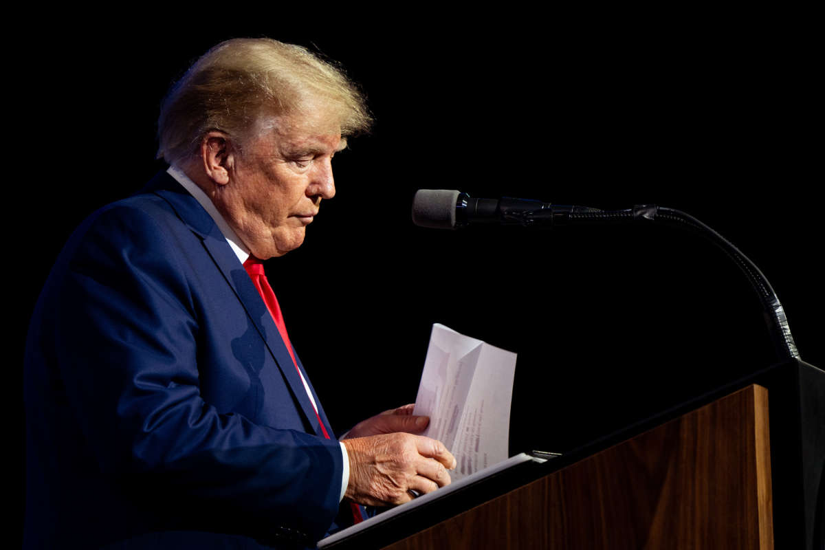 Donald Trump shuffles through papers while standing at a podium