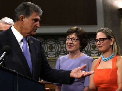 Sen. Joe Manchin speaks as Senators Susan Collins and Kyrsten Sinema (right) listen during a news conference at Dirksen Senate Office Building on July 28, 2021, on Capitol Hill in Washington, D.C.