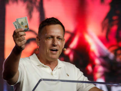 Peter Thiel, co-founder of PayPal, Palantir Technologies, and Founders Fund, holds hundred dollar bills as he speaks during the Bitcoin 2022 Conference at Miami Beach Convention Center on April 7, 2022, in Miami, Florida.