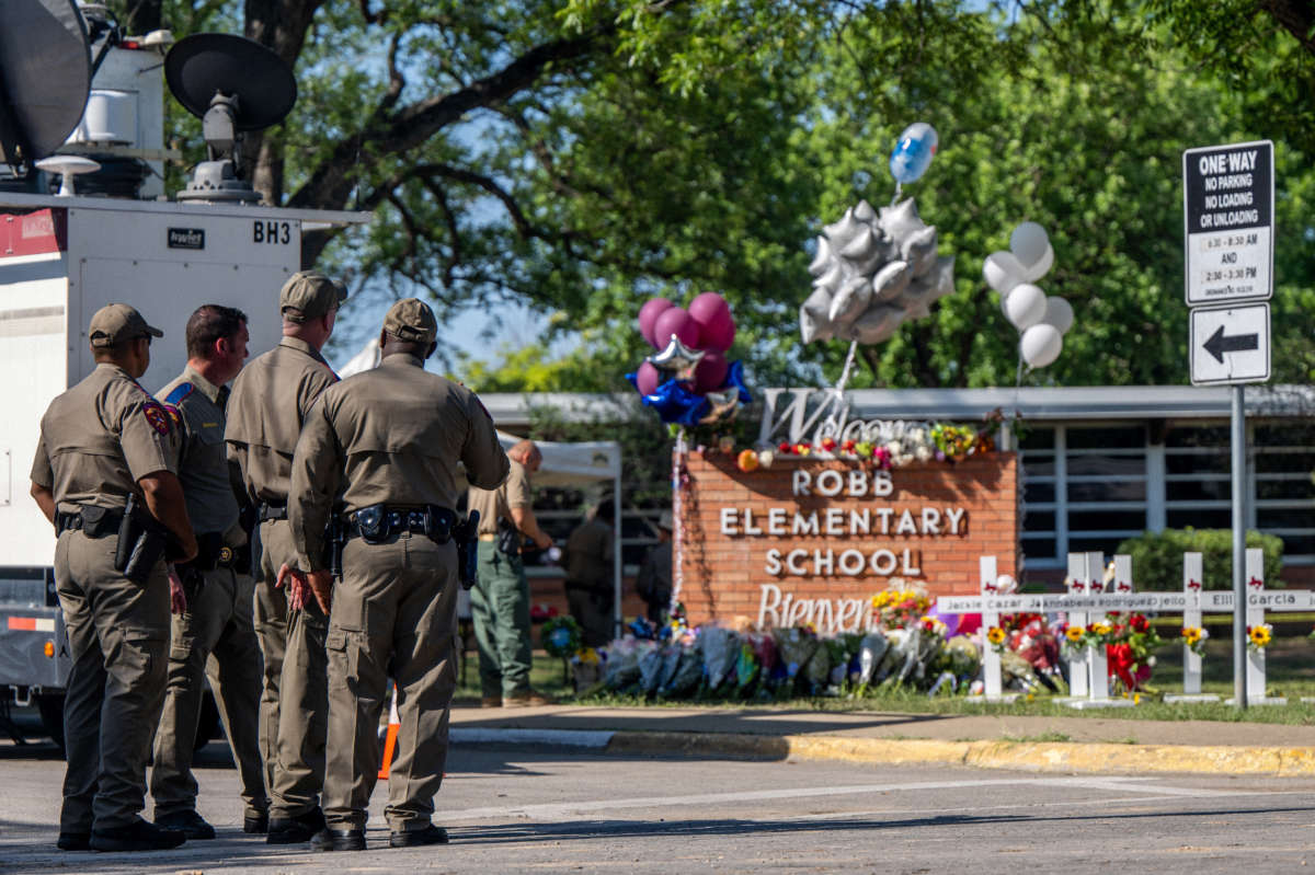Law enforcement officers stand looking at a memorial following a mass shooting at Robb Elementary School on May 26, 2022, in Uvalde, Texas.