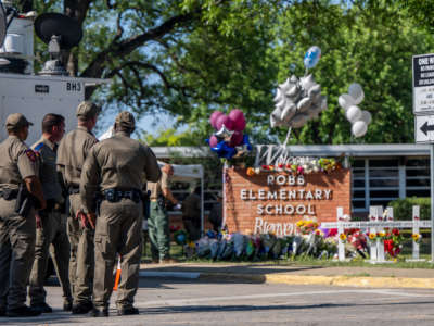 Law enforcement officers stand looking at a memorial following a mass shooting at Robb Elementary School on May 26, 2022, in Uvalde, Texas.