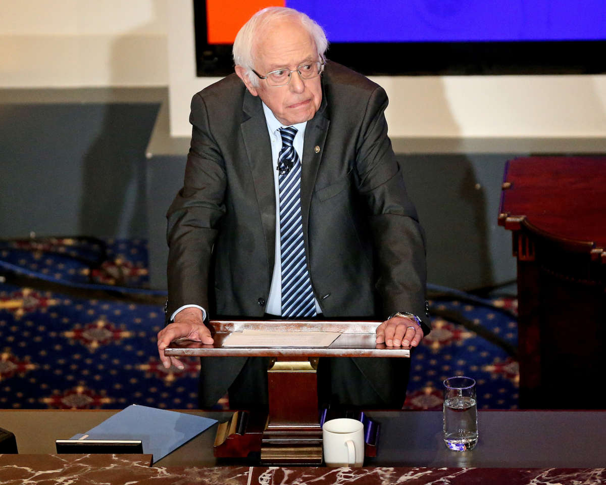 Bernie Sanders leans on the podium at which he speaks