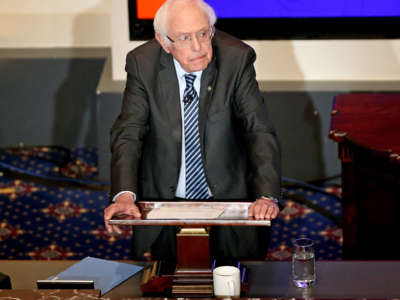 Bernie Sanders leans on the podium at which he speaks