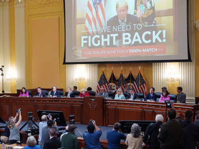 The January 6 Committee meets under a projection screen showing Trump calling for his supporters to "fight back"