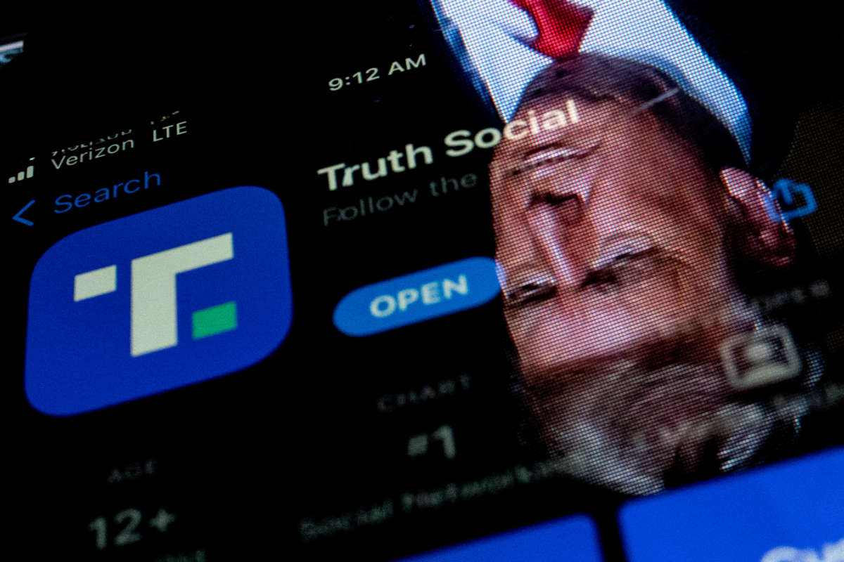 This photo illustration shows an image of former President Donald Trump reflected in a phone screen that is displaying the Truth Social app, in Washington, D.C., on February 21, 2022.