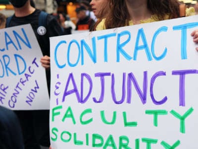 A protester holds a sign reading "Contract and adjunct faculty solidarity" during an outdoor protest
