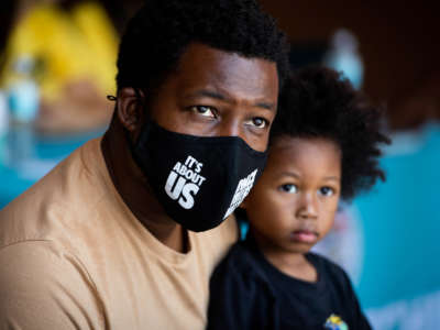 Jelani Hendrix and his three-year-old son L.J. staff the Black Alliance For Just Immigration (BAJI) booth at a Juneteenth celebration at Magic Johnson Park in Willowbrook, California, on June 17, 2022.