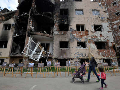 A woman and her daughter walk past a residential building destroyed as a result of shelling in the town of Irpin, near the Ukrainian capital of Kyiv on June 16, 2022.