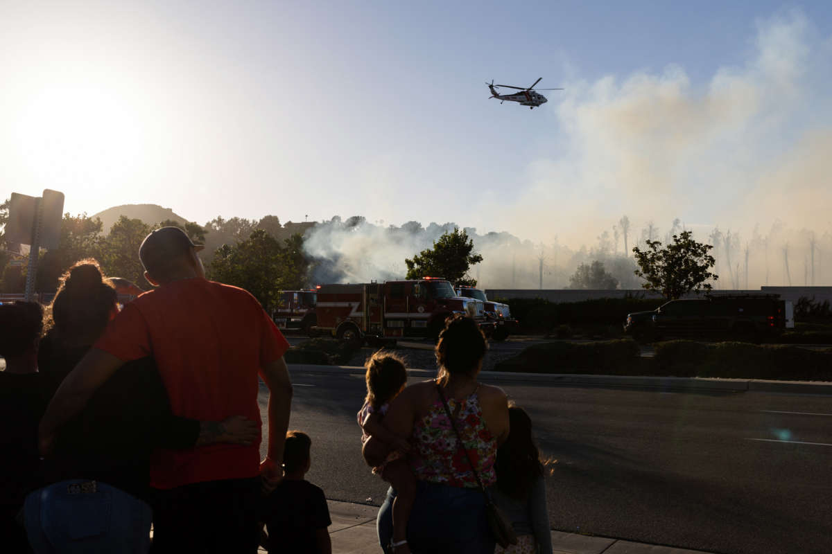 A water-dropping helicopter battles a brush fire that broke out on June 17, 2022, in Jurupa Valley, California.