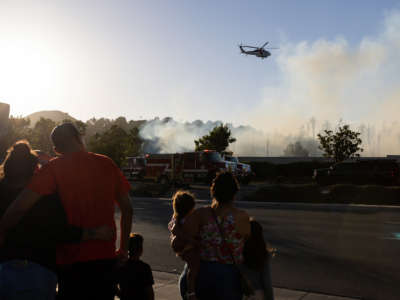 A water-dropping helicopter battles a brush fire that broke out on June 17, 2022, in Jurupa Valley, California.