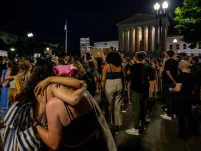 People embrace during a candlelight vigil in front of the U.S. Supreme Court to denounce the court's decision to end federal abortion rights protections on June 26, 2022, in Washington, D.C.