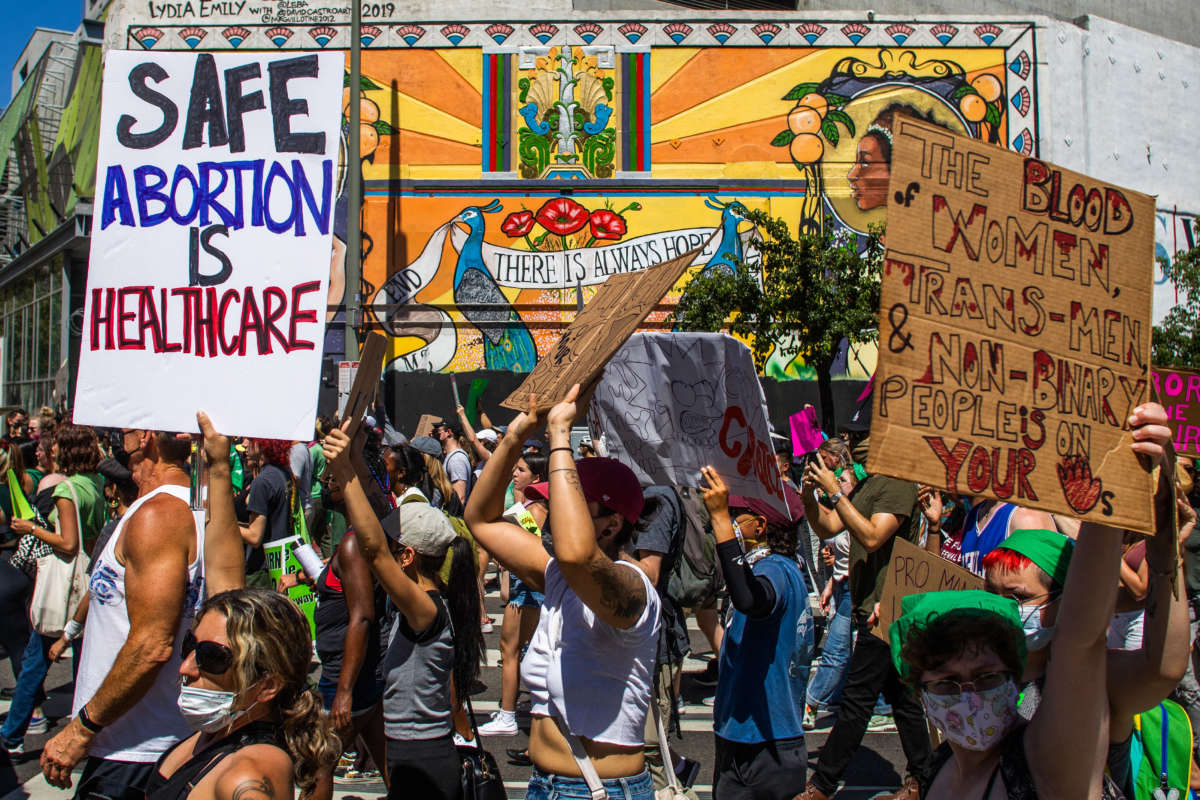 People hold placards as they protest in downtown Los Angeles on June 26, 2022.