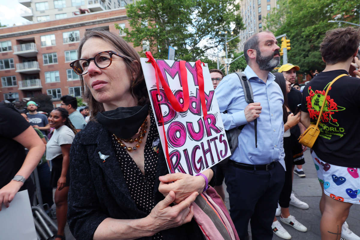 A protester holds a sign reading "MY BODY, OUR RIGHTS" during a protest