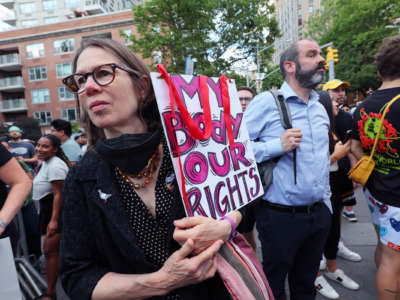 A protester holds a sign reading "MY BODY, OUR RIGHTS" during a protest