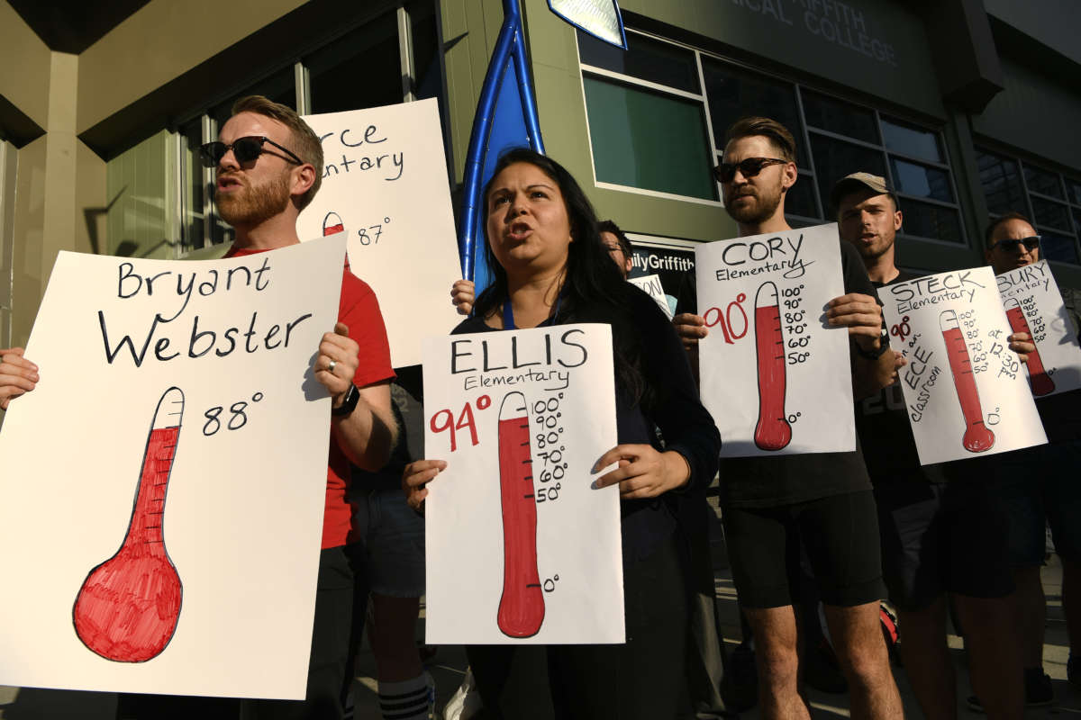 People hold up signs as they take part in a protest outside of the Denver Public Schools administration building to demand equity for students attending classes in excessively hot classrooms on August 26, 2019, in Denver, Colorado.