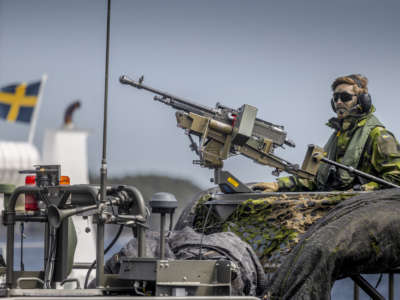 A Swedish soldier sits on a military boat with a machine gun during the Baltic Operations NATO military drills on June 11, 2022, in the Stockholm archipelago on Sweden's eastern coastline.