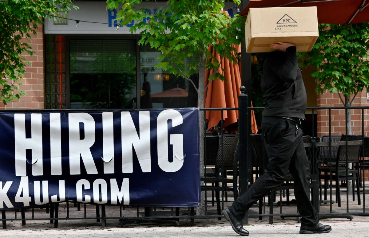 A man walks past a now hiring sign posted outside of a restaurant in Arlington, Virginia on June 3, 2022.