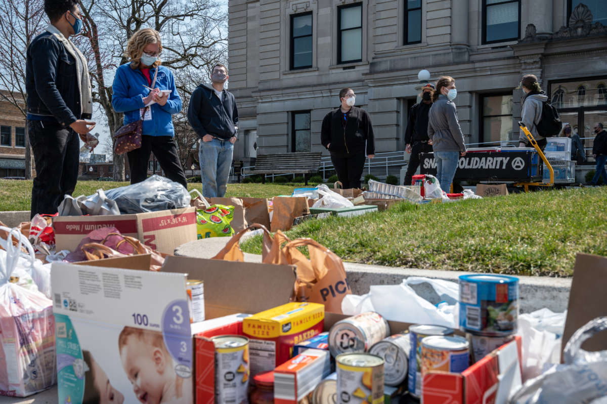 Activists take inventory of donated foods while others stand and talk during a Day of Solidarity event at the DeKalb County Court House on April 3, 2021, in Auburn, Indiana.