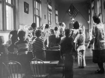 Children in a school at Ellis Island pledge allegiance to the U.S. flag, around 1940-1950.